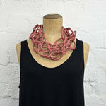 Red brick coloured rubber chain necklace on a display model.