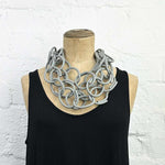 Grey coloured rubber chain necklace on a display model.