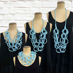 Light blue rubber necklace on a set of mannequins displaying the variety of ways the necklace can be worn.