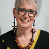 woman wearing a wooden pebble dangling earrings and necklace