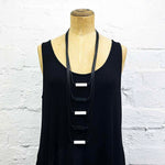 Long drop necklace with black and white coloured small blocks displayed on a headless wooden mannequin