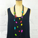Colourful tiles on a multi strand necklace on a wooden mannequin.