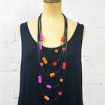 Multi strand necklace with red, orange and pink plastic beads on a mannequin
