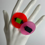 Hand of a mannequin displaying two large chunky colourful resin rings