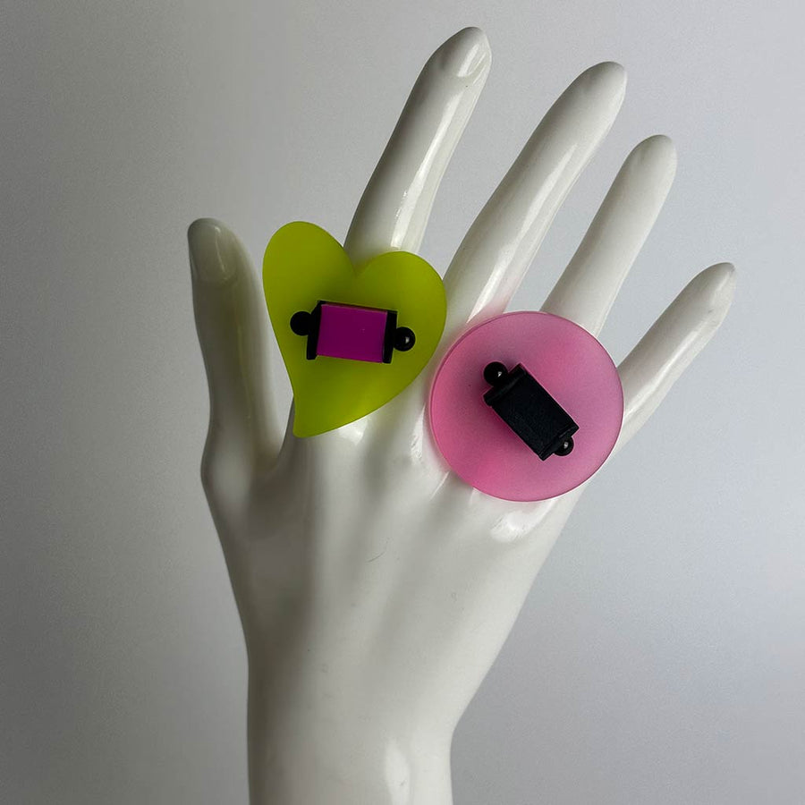 Hand of a mannequin displaying two large chunky colourful resin rings