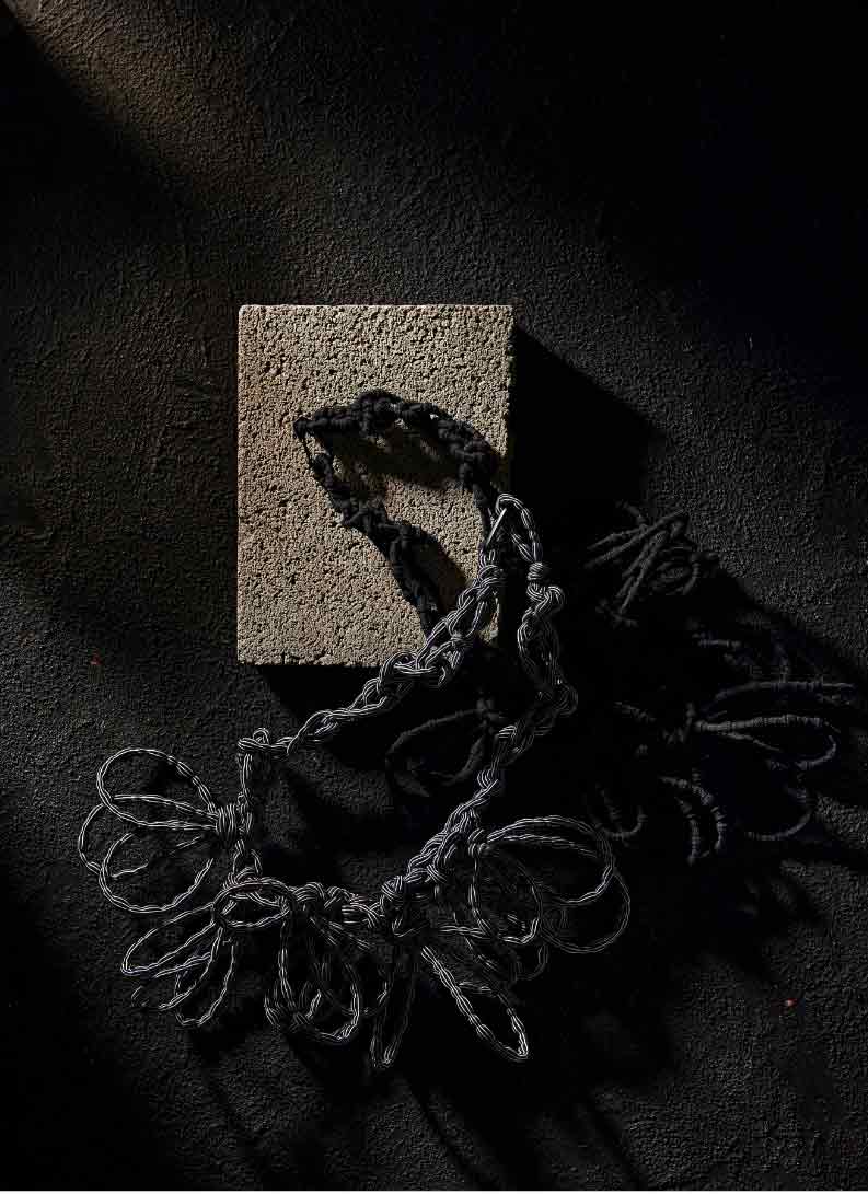 black textile necklace on a stone and dark backdrop
