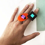 Hand wearing two colourful rings on a light background