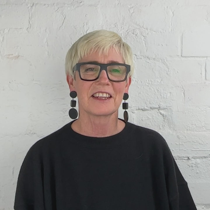 woman wearing a pair of black dangle earrings demonstrated in a video