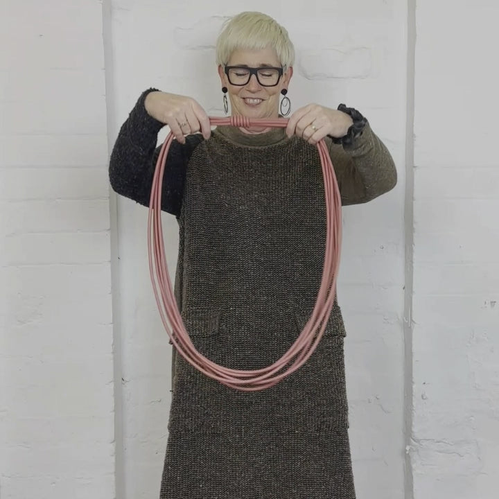 video demonstratino of a woman wearing a long brick-colored rubber necklace