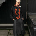 Rowan wearing black top and skirt and wearing recycled rubber necklace in black and tan and lightweight rubber earrings and bangles.