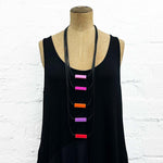 Long drop necklace with purple and orange coloured small blocks displayed on a headless wooden mannequin