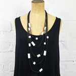 Multi strand necklace with white plastic beads on a mannequin