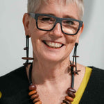 woman wearing a wooden pebble necklace and a pair of wooden dangling earrings