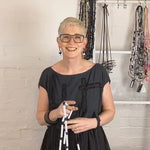 woman demonstrating how to wear black and white rod necklaces on a video