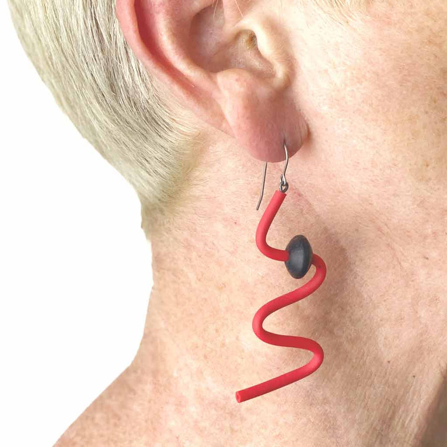 woman wearing red squiggle earrings with black beads