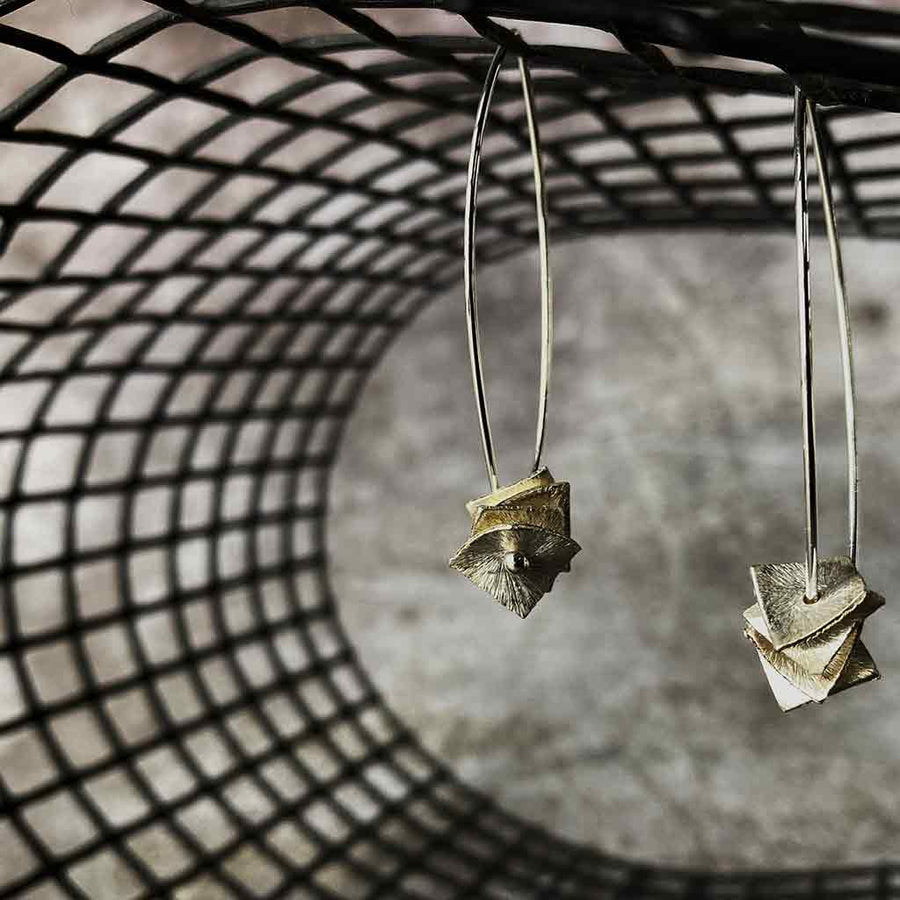 silver drop earrings with silver square disks on a net backdrop
