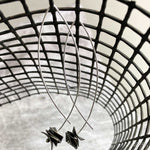 silver drop earrings with dark square disks on a net backdrop