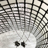 silver drop earrings with dark square disks on a net backdrop