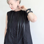 woman wearing a long black layered necklace