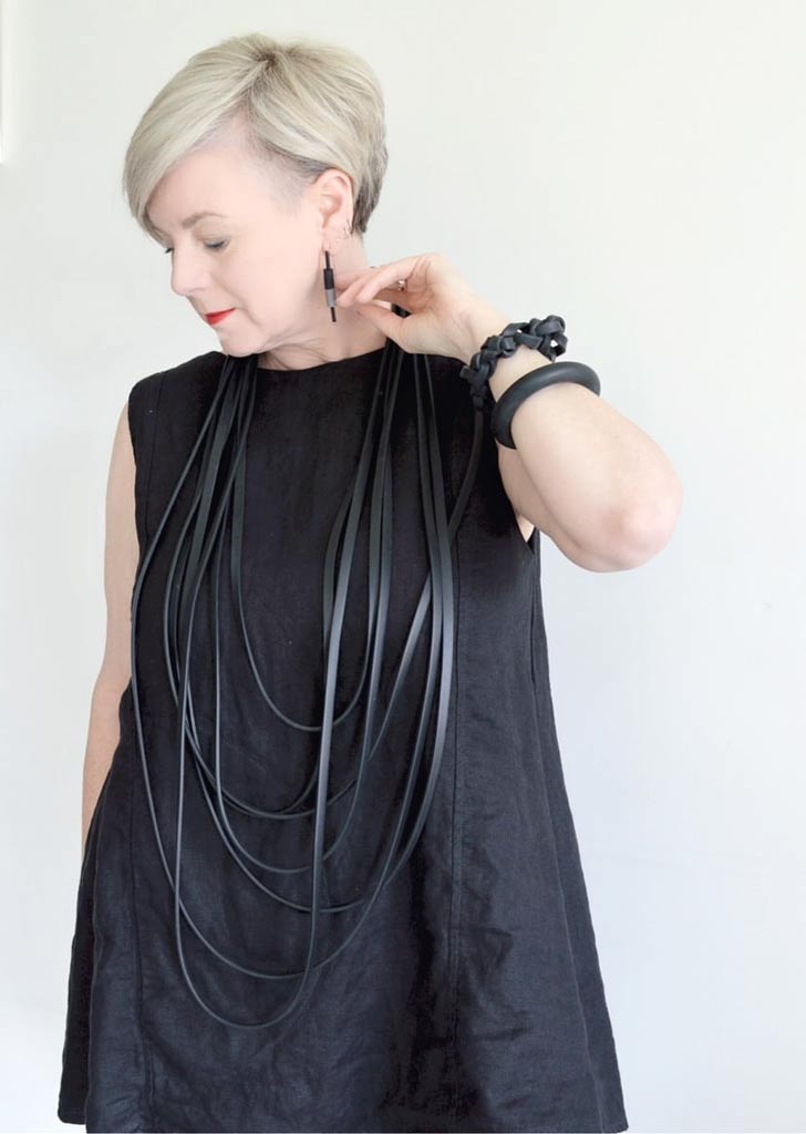 woman wearing a long black layered necklace