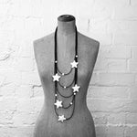 A black and white image of a layered necklace with white star pendants on a mannequin.