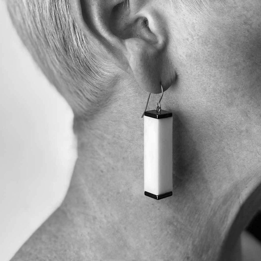 greyscale photo of tower earrings worn by a woman
