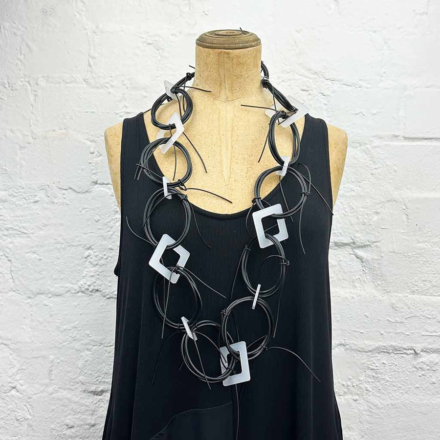 Long chaotic necklace recycled materials with white squares and black rubber o rings