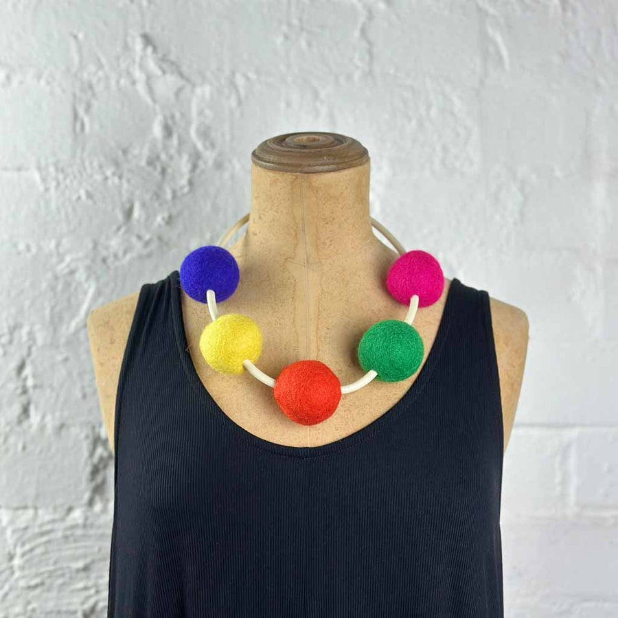 multi-colored 5 felt bead necklace on a mannequin. colors: blue, yellow, orange, green, fuchsia pink
