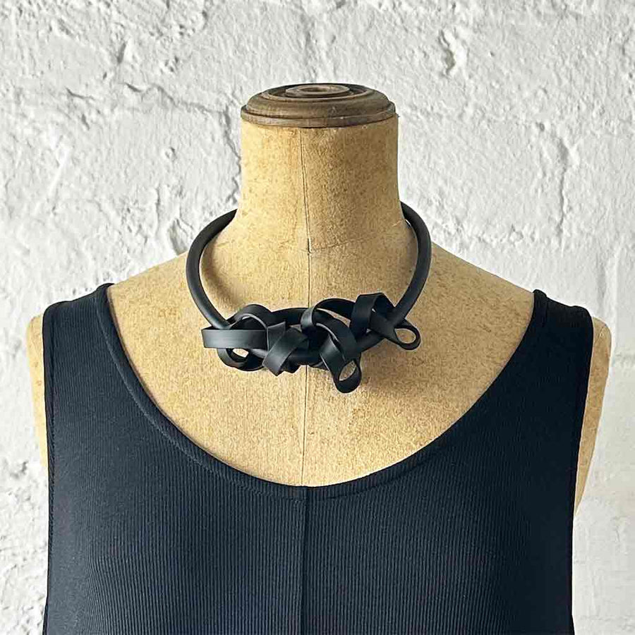 black rubber tangled necklace on a mannequin