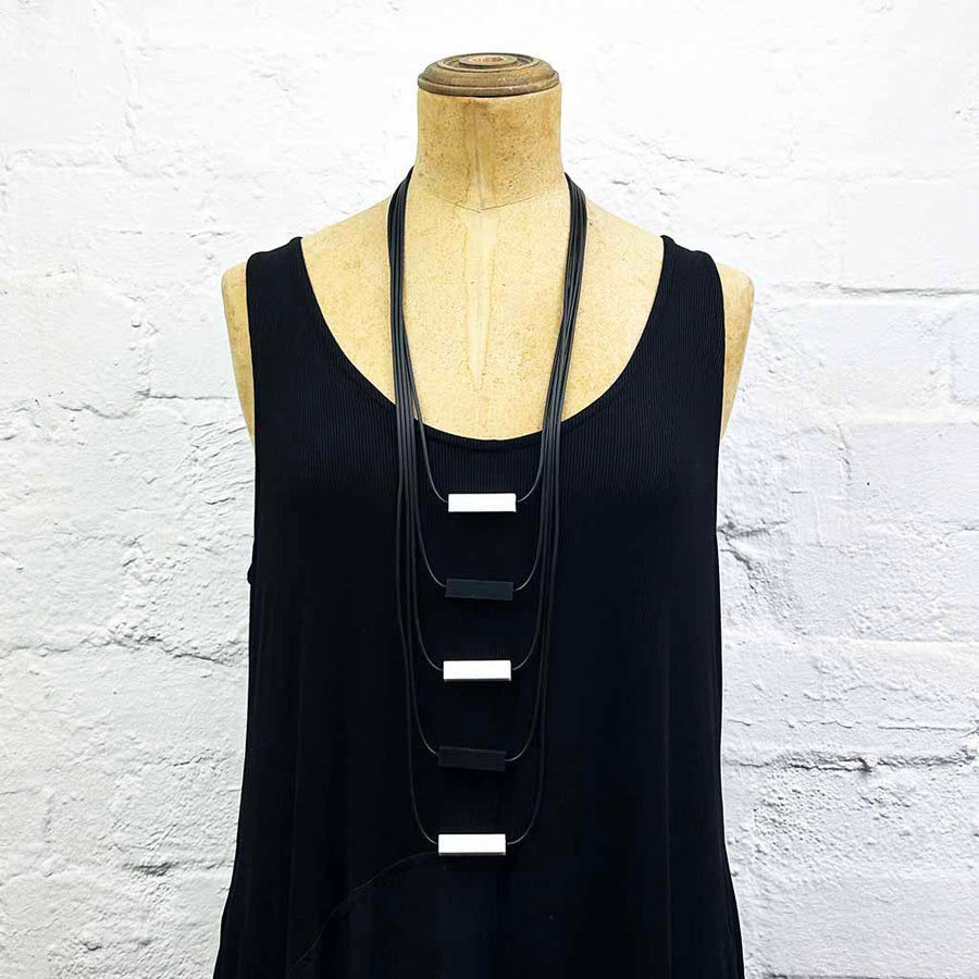 Long drop necklace with black and white coloured small blocks displayed on a headless wooden mannequin 