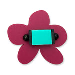 Pink flower-shaped ring with a turquoise centre on a white background