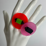 Hand of a mannequin displaying two large chunky colourful resin rings