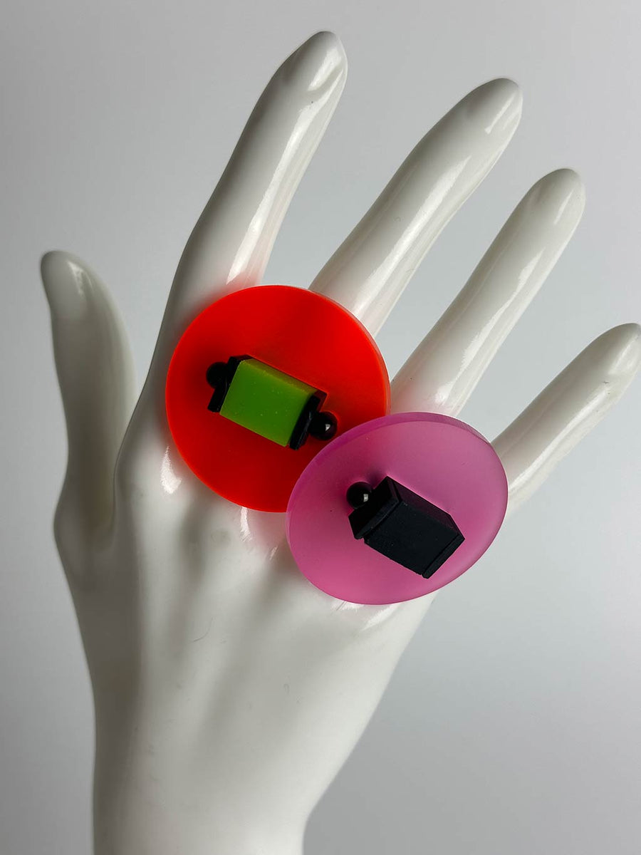 Hand of a mannequin displaying two large chunky colourful resin rings