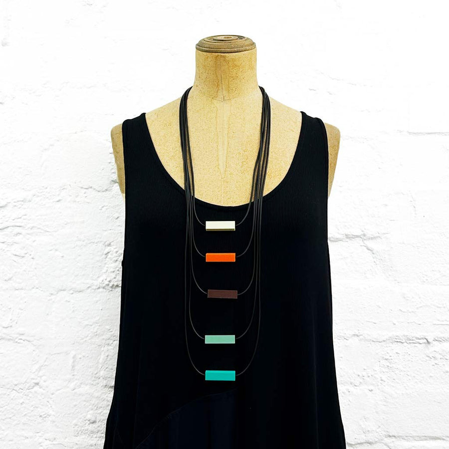 Long drop necklace with orange, brown and blue block details on a mannequin 