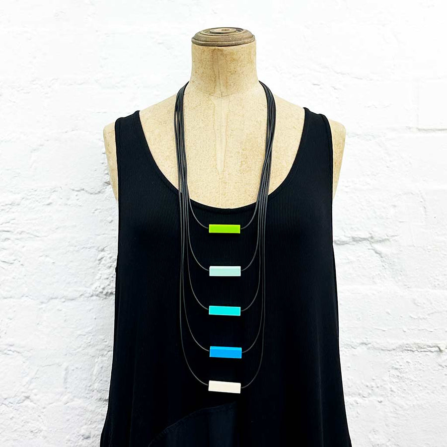 Long drop necklace with green and blue  block details on a mannequin