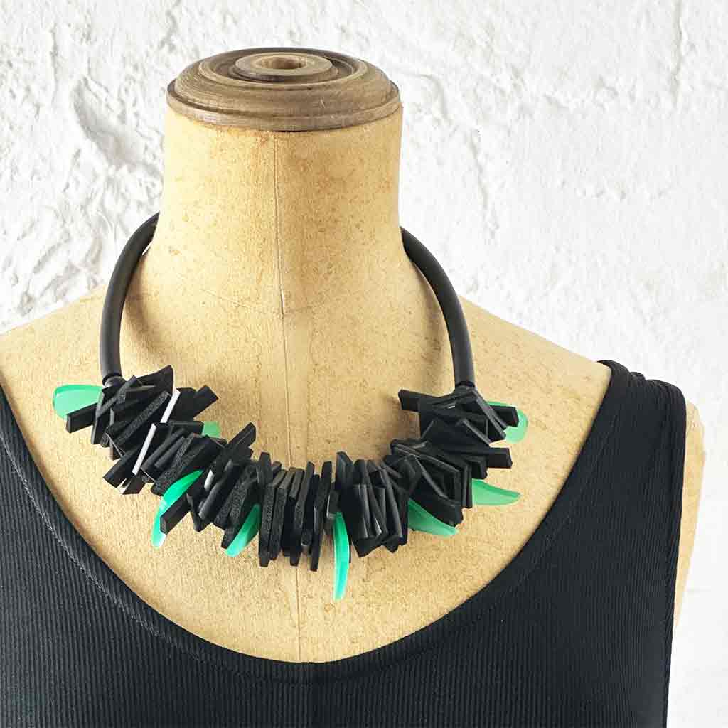 Black and green structured necklace on a neck mannequin