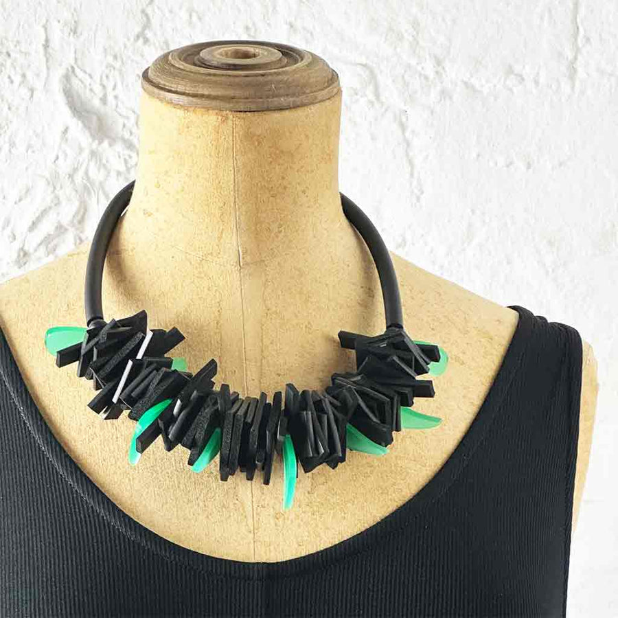 Black and green structured necklace on a neck mannequin
