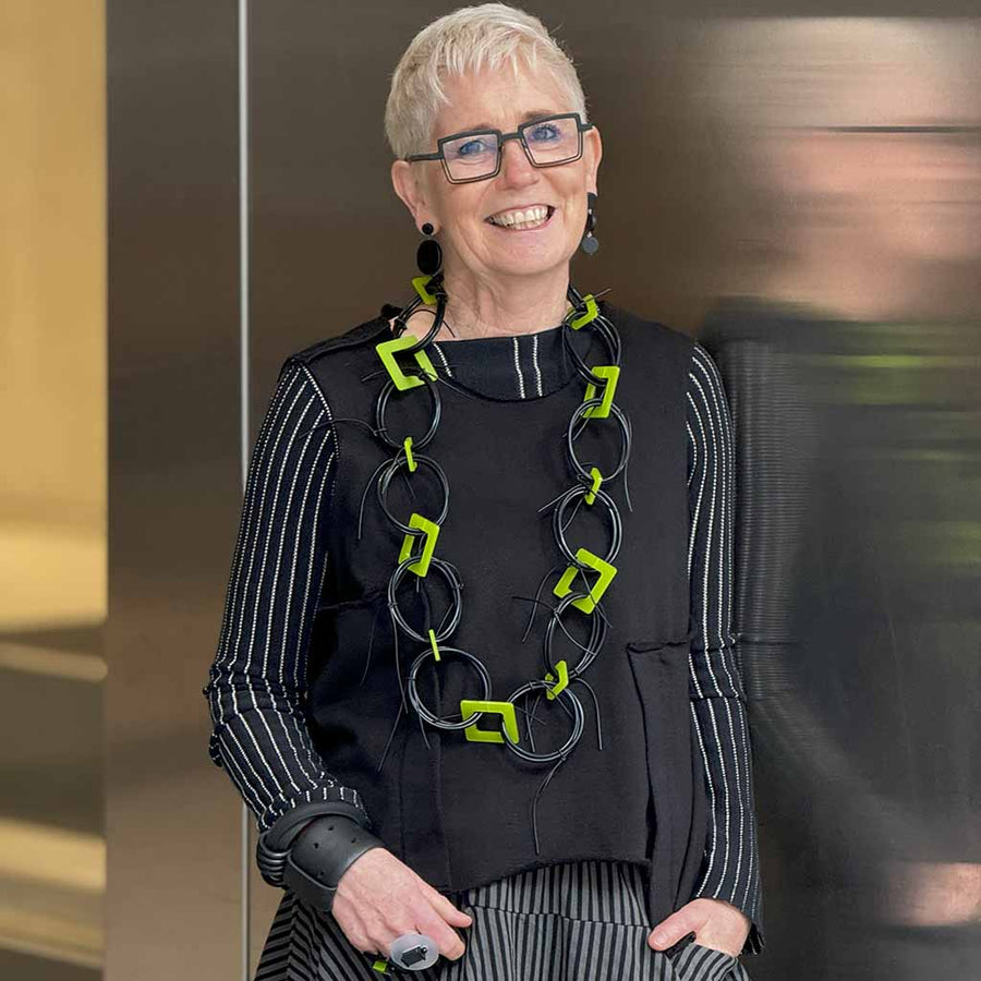 Photo of Rowan, designer of Jewellery at Frank Ideas wearing long black and lime green necklace.