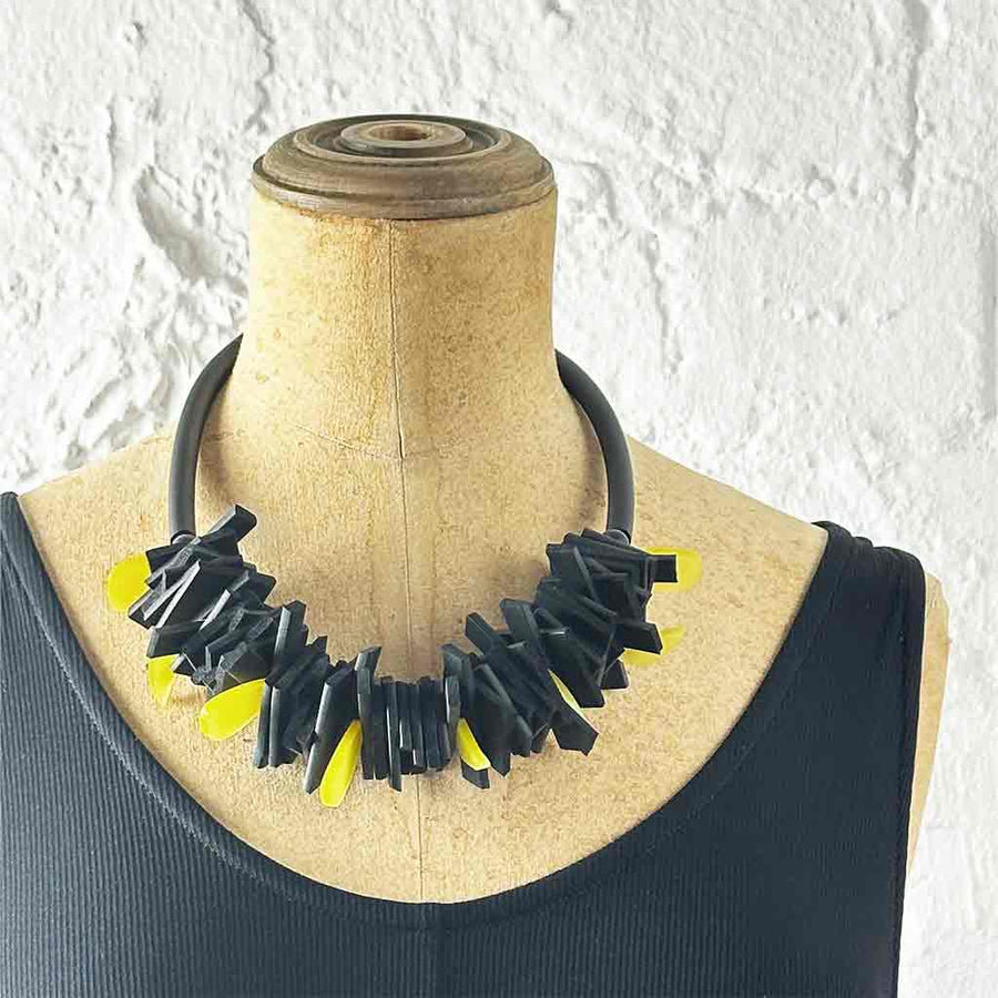 Black and yellow structured necklace on a neck mannequin