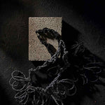 black textile necklace on a stone and dark backdrop