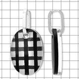 Close-up of gloss black and white gingham Perspex oval huggie earring by Frank Ideas
