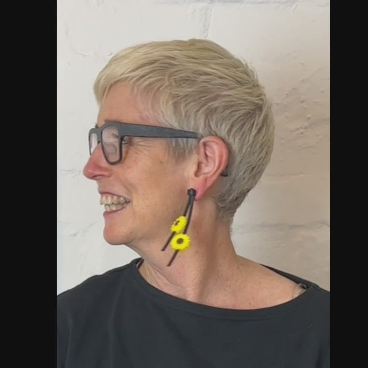woman wearing asymmetric sunflower earrings on a video demonstration