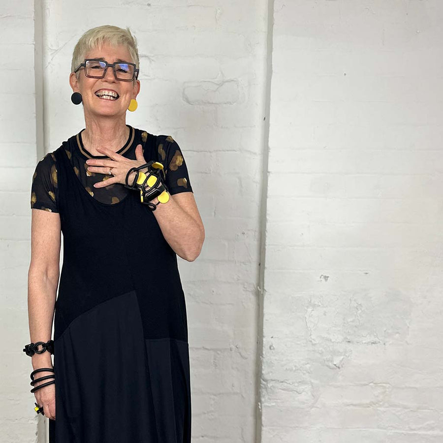 Rowan wearing yellow and black resin and rubber necklace and matching dot earrings and rubber bracelets.