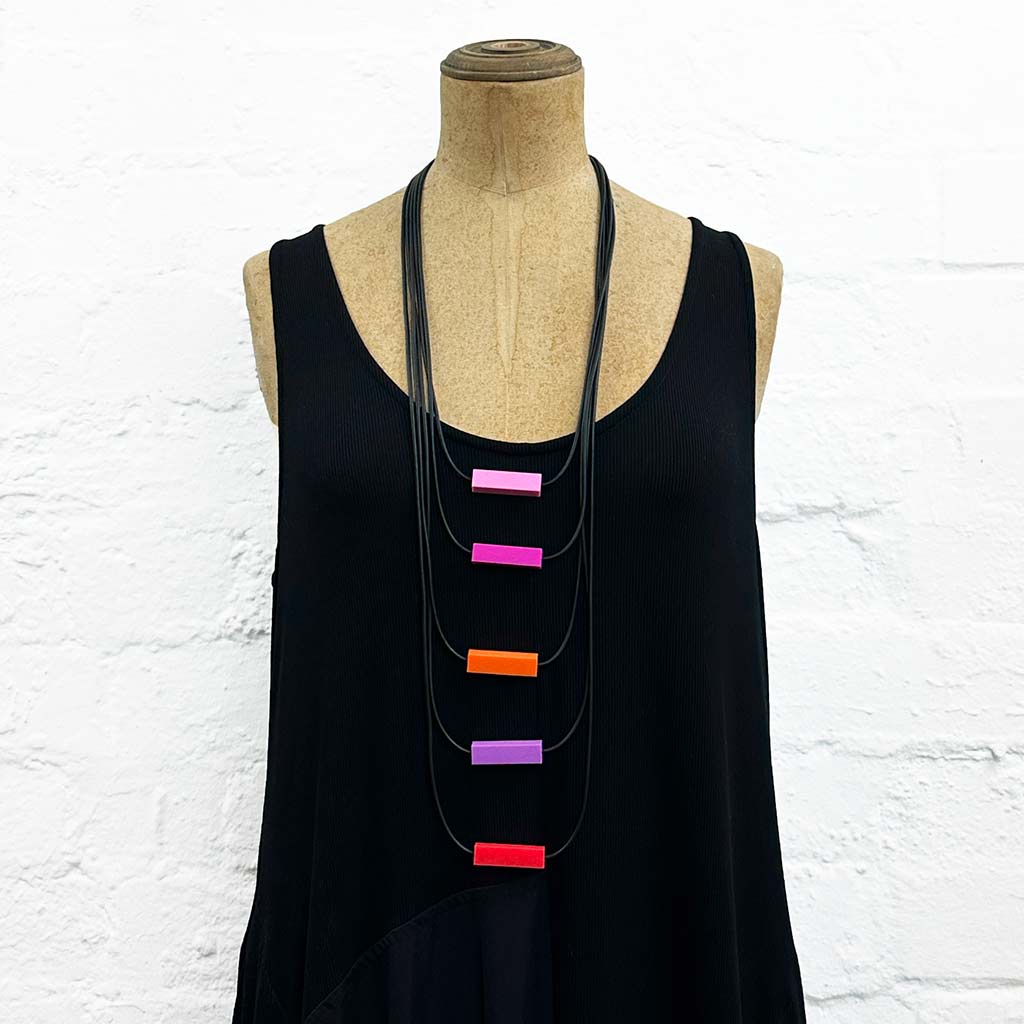 Long drop necklace with purple and orange coloured small blocks displayed on a headless wooden mannequin