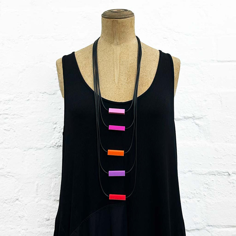 Long drop necklace with purple and orange coloured small blocks displayed on a headless wooden mannequin