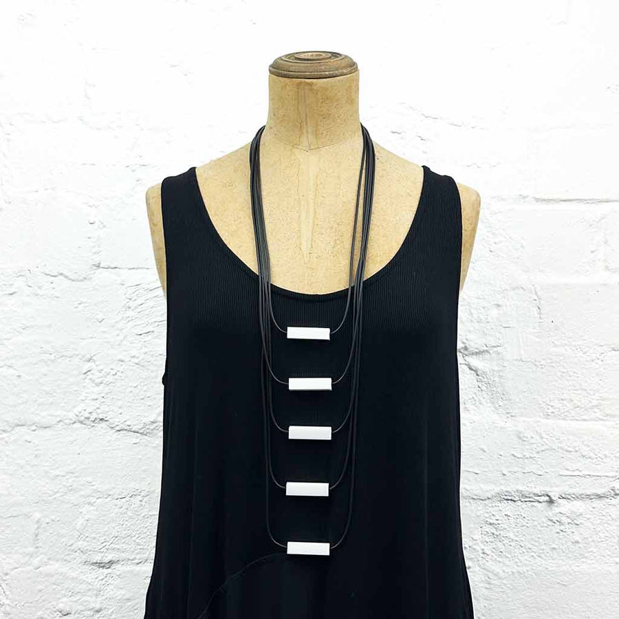 Long drop necklace with black and white small blocks displayed on a headless wooden mannequin 