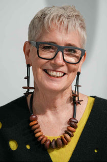 woman wearing a wooden pebble necklace and a pair of wooden dangling earrings