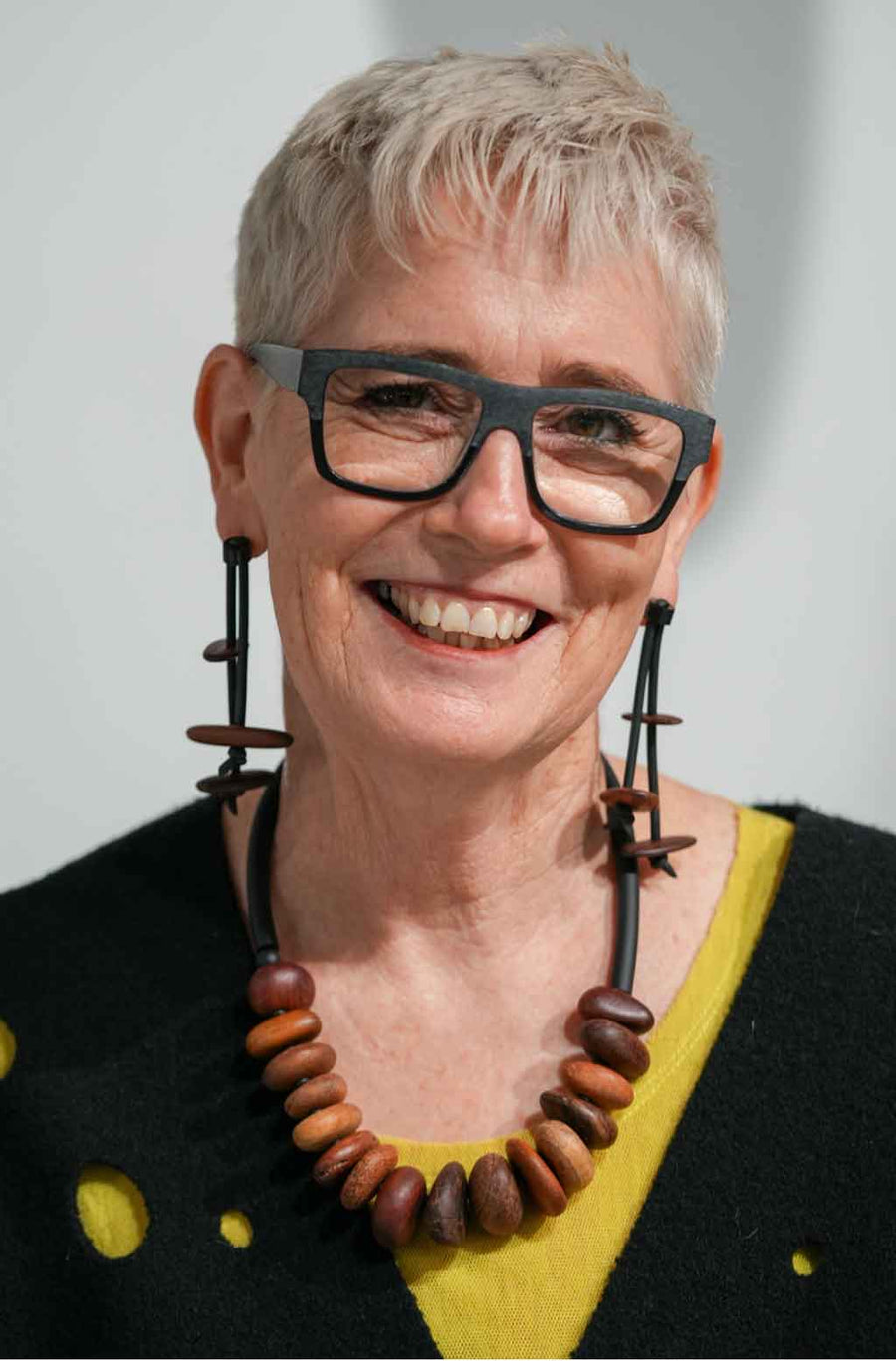 woman wearing a wooden pebble necklace and a pair of wooden dangling earrings