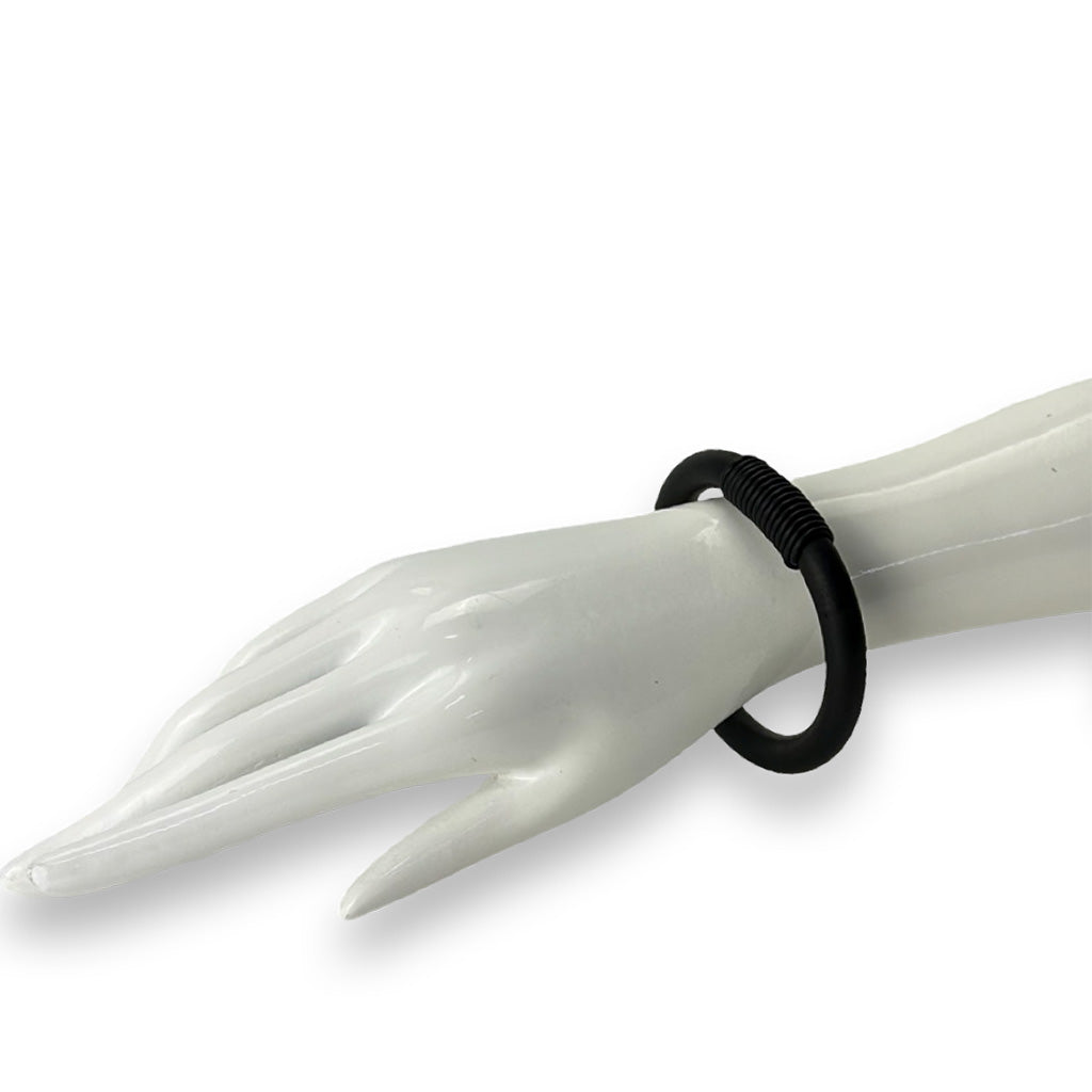 Black bangle on a mannequin hand against a white background