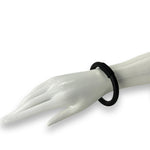 Black bangle on a mannequin hand against a white background